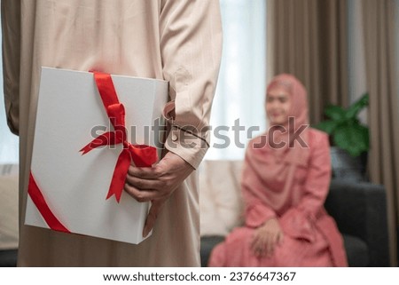 Rear view of a husband hiding a Gift from his wife. 