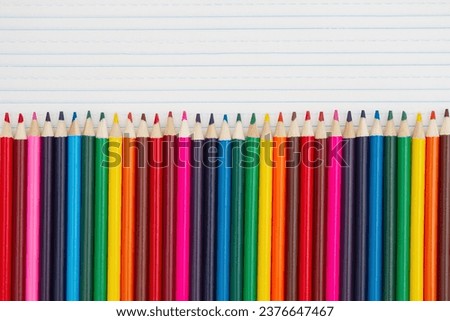 Color pencils crayons on vintage ruled line notebook paper background for you education or school message Royalty-Free Stock Photo #2376647467