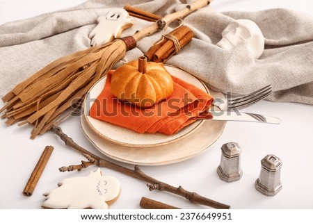 Halloween table setting with tasty pumpkin shaped bun and broom on light background, closeup
