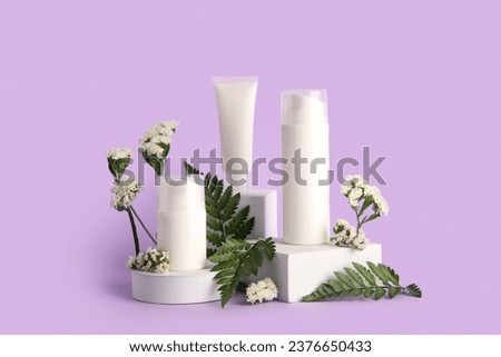 Composition with different cosmetic products, plaster podium and beautiful flowers on purple background