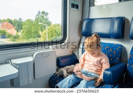 Beautiful Little girl using digital tablet during traveling by railway in Europe. High quality photo