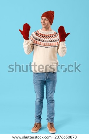 Young man in winter clothes on blue background