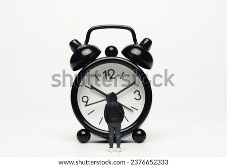 Selective focus of miniature staring alarm clock on white background.