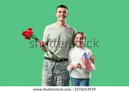 Soldier and his little daughter with USA flag on green background. Veterans Day celebration