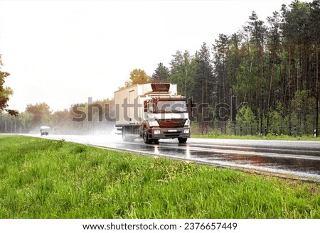 A refrigerated truck transports perishable food cargo on a slippery highway in rainy weather. Royalty-Free Stock Photo #2376657449