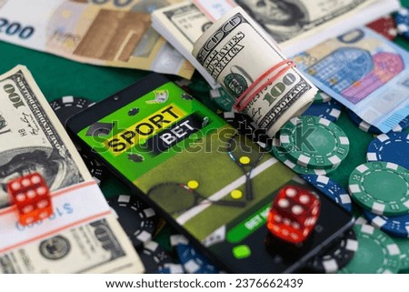 Money, mobile phone and rugby ball on dark wooden background. Concept of sports bet. Royalty-Free Stock Photo #2376662439