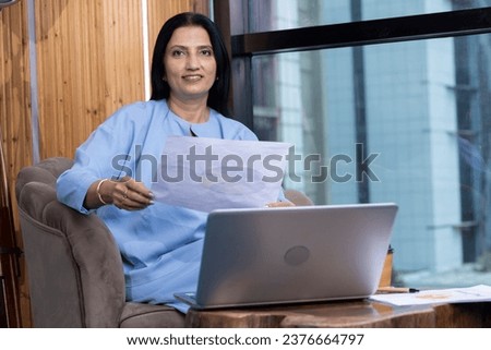 Businesswoman using laptop on sofa at office