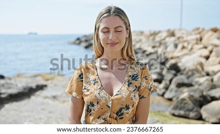 Young blonde woman breathing with closed eyes at seaside