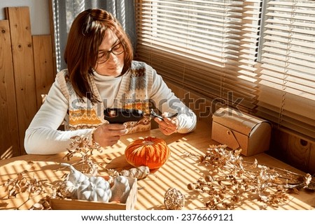 Woman making orange velvet fabric pumpkin. Autumn decoration with handmade textile pumpkin on wooden table. Fall vibes. Thanksgiving decor.