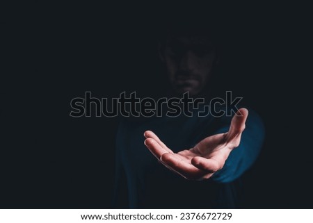 Male hand holding showing or giving something over black background, copy space for text.