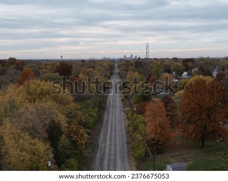 An aerial shot of railroad tracks leading to downtown Indianapolis surrounded by colorful trees in autumn