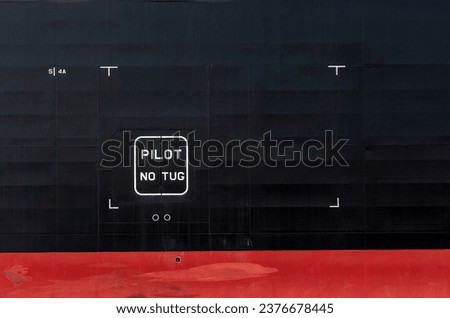 Close up of section of the black and red hull of a ship with letters PILOT No Tug 