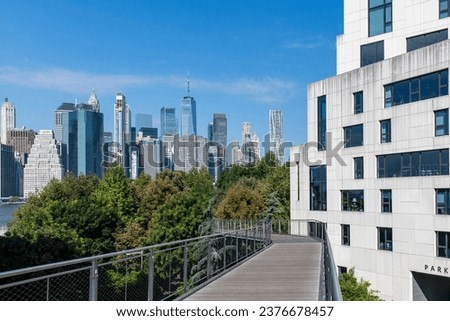 High angle view of Squibb Park Bridge in Brooklyn Bridge Park, Brooklyn Heights, New York City, NY, USA with panoramic view of skyscrapers and landmarks of Lower Manhattan against a clear blue sky