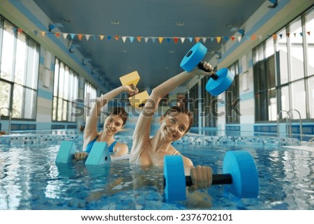 Two beautiful training women enjoying water gymnastics training class at pool