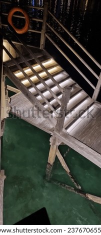 Night picture of stairs made of wood to go down to the sea with lamp illuminating the way