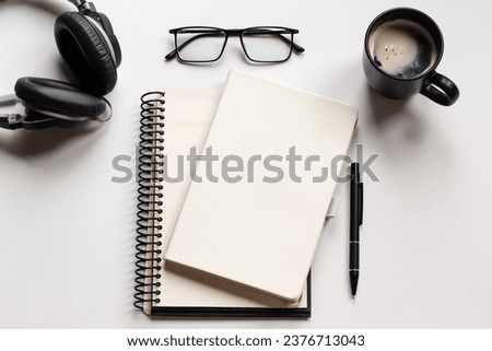 Creative flat lay photo of workspace desk. Top view office desk with glasses, pen, notebooks, coffee cup and headphones on white background. Top view with copy space, flat lay photography.