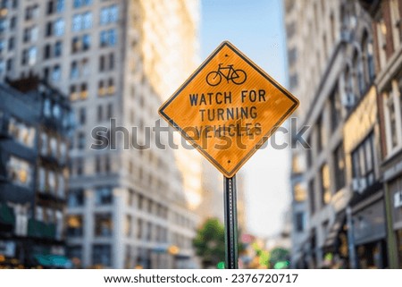 A warning sign for cyclists, '"watch for turning vehicles", on a street in New York.