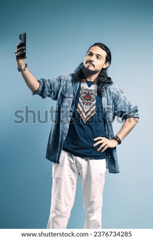 Portrait of a Brazilian wearing a button-down shirt and jeans, with one hand on his waist and the other holding his cell phone, taking a selfie - Belém - Pará - Brazil