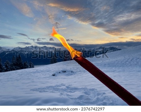Close up of torch, winter landscape at twilight in the background. High quality photo