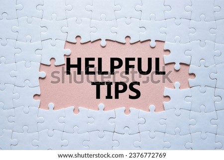 Helpful tips symbol. White puzzle with words Helpful tips. Beautiful pink background. Business and Helpful tips concept. Copy space. Royalty-Free Stock Photo #2376772769