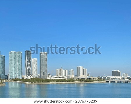 Under the expansive Miami sky, the city's stunning skyline rises majestically from the tranquil sea, a picture of coastal serenity and urban vibrance."