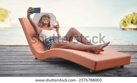 Selfie, travel and woman with water, summer and happiness on a sun lounger, cocktail and tropical island. Female person, girl or happy tourist on a break, social media and drink to relax and cheerful Royalty-Free Stock Photo #2376788003