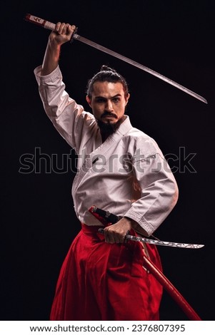 portrait of a brazilian man with samurai costume, holding two swords horizontally and looking at the camera - Belém - Pará - Brazil Royalty-Free Stock Photo #2376807395