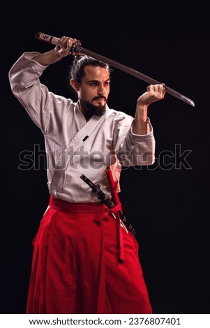 portrait of a brazilian with samurai costume, holding his sword with one hand, and with the other hand holding the blade - Belém - Pará - Brazil Royalty-Free Stock Photo #2376807401
