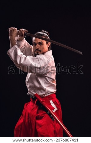 portrait of a brazilian man with samurai costume, holding his sword with both hands horizontally and looking at the camera - Belém - Pará - Brazil Royalty-Free Stock Photo #2376807411
