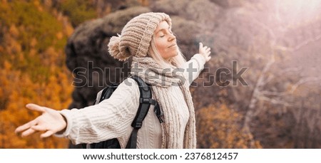 Freedom traveler woman standing with raised arms and enjoying a beautiful nature. Female breathing clean air with eyes closed Royalty-Free Stock Photo #2376812457
