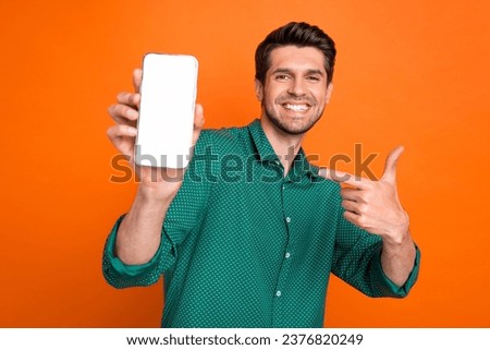 Photo of young man student wear green shirt point finger smartphone gadget modern app display web store isolated on orange color background