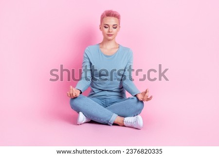 Full length photo of dreamy pretty lady wear blue shirt sitting legs crossed enjoying yoga isolated pink color background