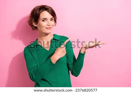 Photo of adorable girl with bob hairdo dressed green shirt directing at product on arm empty space isolated on pink color background