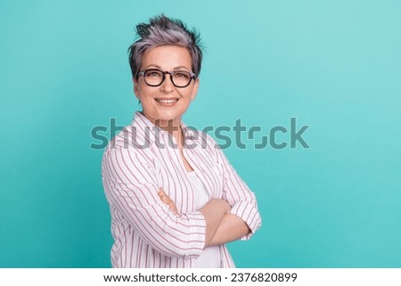 Portrait of charming aged business woman standing near empty space with crossed arms isolated teal color background