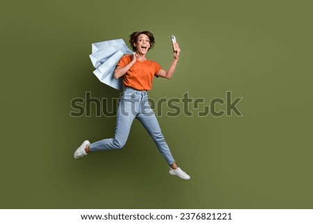 Full length photo of excited girl in stylish clothes doing selfie on smartphone jump with new outfit isolated on green color background