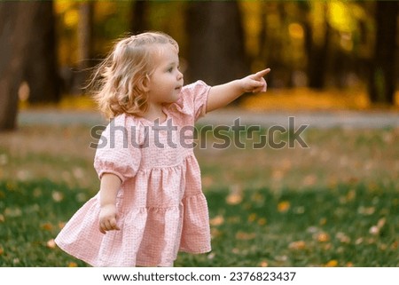 Portrait of smiling little girl walks in the rays of a sunset, enjoying the autumn, warmth, flowers, freedom. Child having fun outdoors Royalty-Free Stock Photo #2376823437