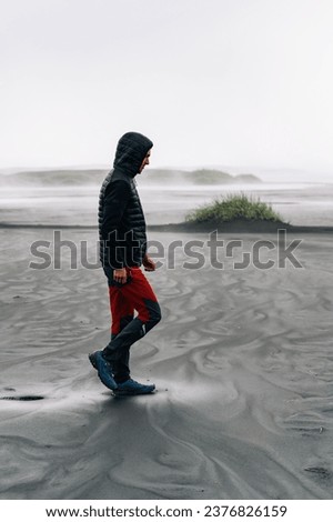 An explorer is discovering and exploring the untouched and wild nature of Iceland. A man is walking on the ocean shore in Iceland.