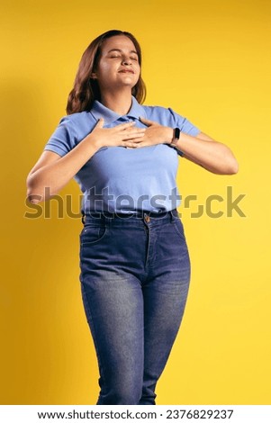 Portrait of a Brazilian woman, wearing a polo shirt and jeans, with both hands resting on her chest, grateful, eyes closed - Belém - Pará - Brazil