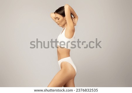 Calm serious asian slim young lady in underwear with perfect body, isolated on gray studio background. Natural beauty care, freshness and lifestyle, weight loss, procedures Royalty-Free Stock Photo #2376832535