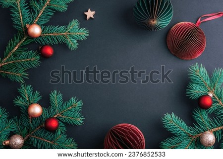 Christmas frame made of fir branches with Christmas balls on black background. Top view, flat lay, copy space.