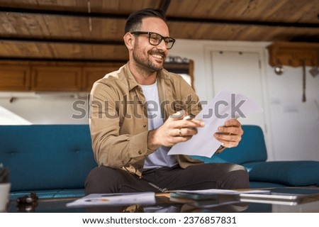 One man mature caucasian male work at home hold paper document sign insurance contract or read report enjoy good news in letter receive official paper about tax refund credit loan approval