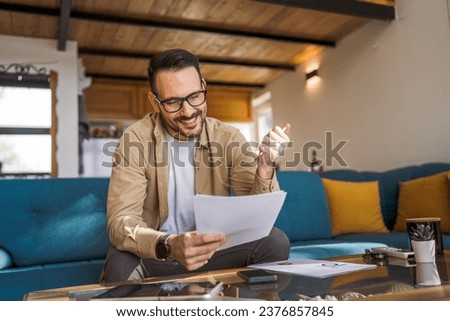 One man mature caucasian male work at home hold paper document sign insurance contract or read report enjoy good news in letter receive official paper about tax refund credit loan approval Royalty-Free Stock Photo #2376857845