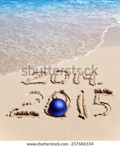 On sand it is written 2014 and 2015 and the New Year's ball lies