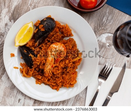 Appetizing racy seafood paella with mussels, prawns and slice of fresh lemon.Traditional Valencian cuisine Royalty-Free Stock Photo #2376863003