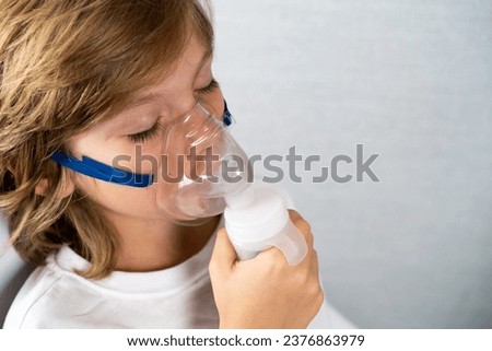 a beautiful child with a cough inhaler mask close-up, flu and cold season. space for text, space for copying, seasonal respiratory diseases, children's medicine. Royalty-Free Stock Photo #2376863979