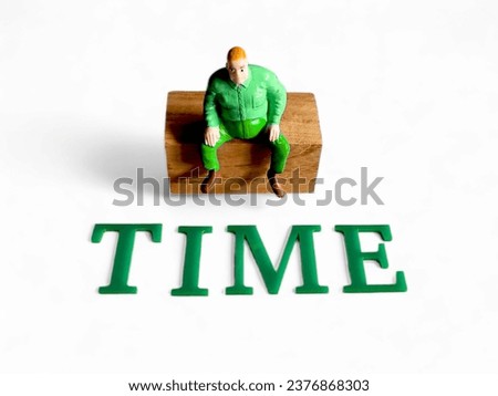 someone was seen sitting on a wooden block and in front of him was the word "time"