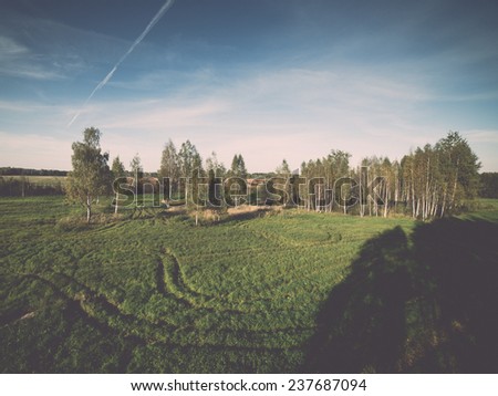 country landscape with fields and blue sky with plane trails - retro, vintage style look