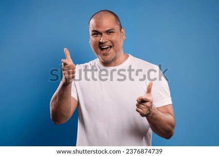 Portrait of a Brazilian man wearing a basic white shirt, facing forward, pointing forward with the index finger of both hands, smiling and looking at the camera - Belém - Pará - Brazil