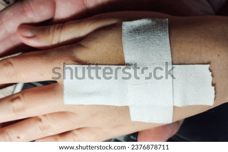 A cross-shaped plaster on a girl's hand. Wound and cut concept. High quality stock photo.