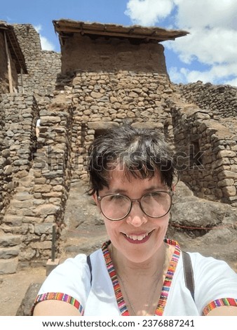 Happy woman in front of a part of Pisaq archaeological site. Peru.